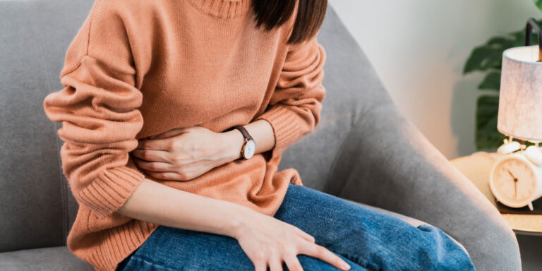 Girl sitting on sofa due to stomachache