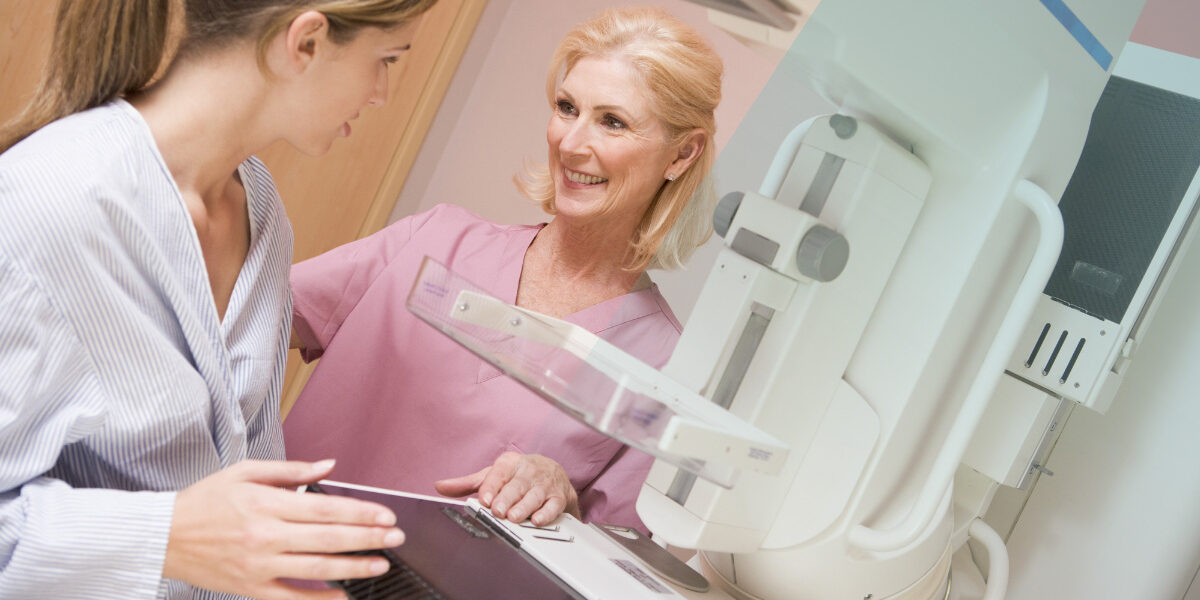 Nurse assisting patient undergoing mammogram in hospital