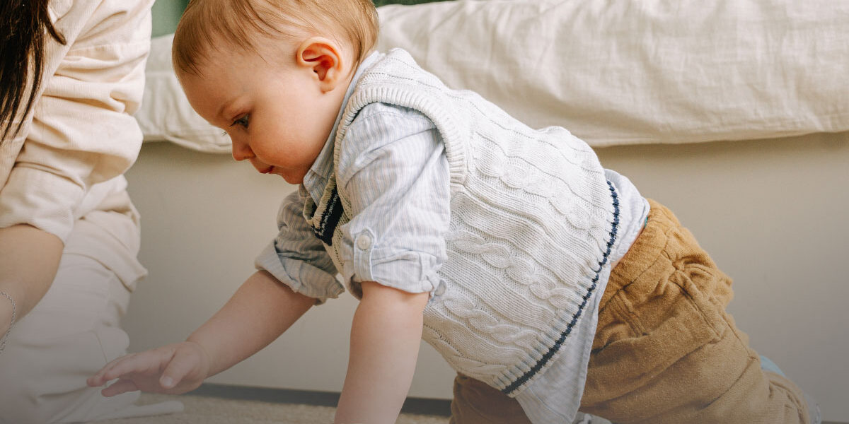 Toddler playing with large wooden blocks under parent supervision in a safe home setting.