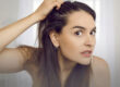 Woman gently examining her hairline at home, representing early awareness of hair thinning and hair loss concerns.