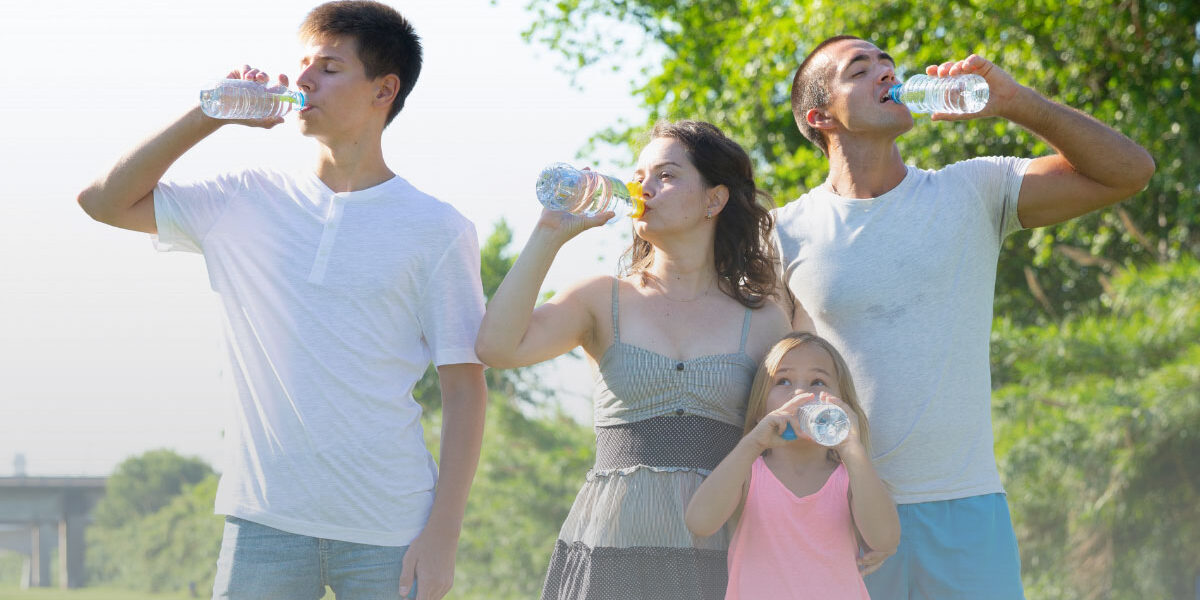 Family drinking water during a summer outdoor activity- Staying hydrated before, during, and after outdoor activities can help prevent dehydration and heat-related illness.