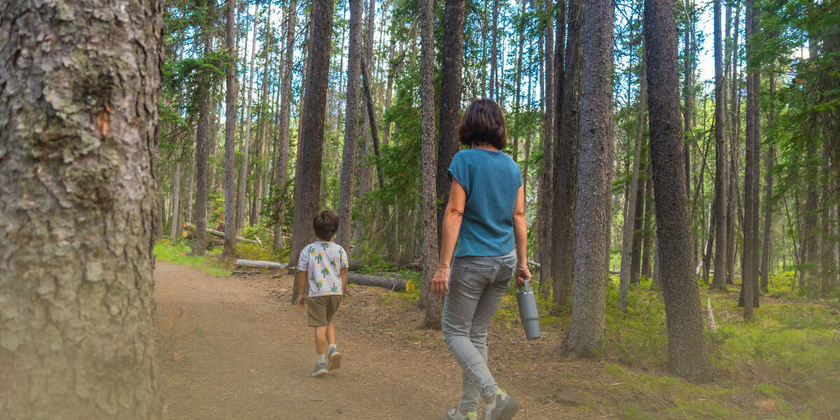 Parent and child walking on a forest trail during tick season, promoting outdoor safety and Lyme disease prevention.