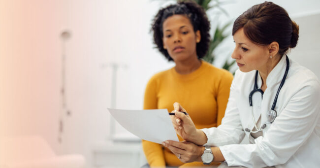 Doctor reviewing medical test results with a female patient during a healthcare consultation.