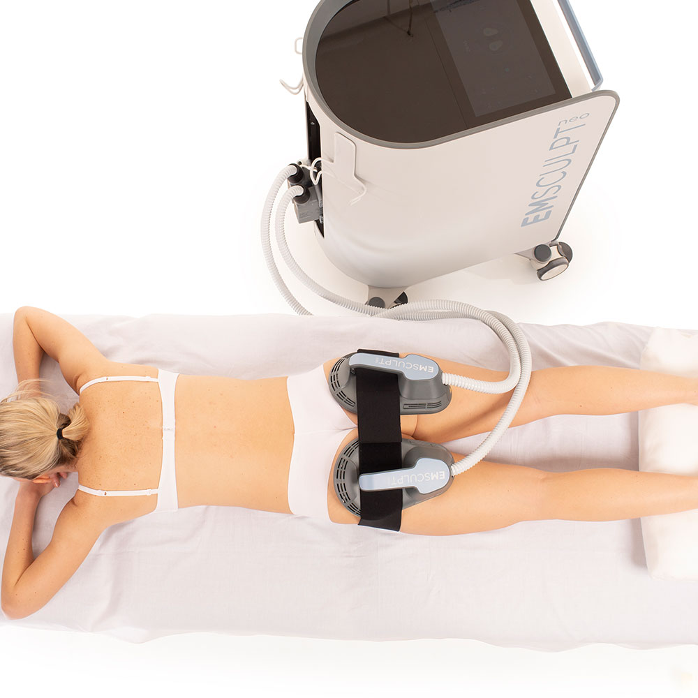 Patient receiving EMSCULPT NEO body contouring treatment with applicators positioned on the thighs.